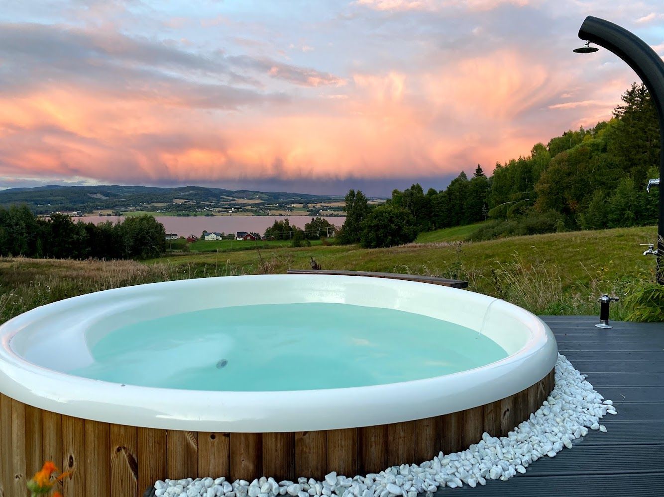 Badestamp med turkist vann og trebenker i solnedgang over Mjøsa