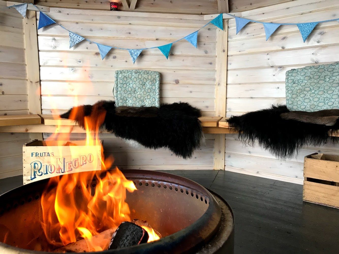 Bålhus med flammer i bålpannen, skinn på benkene og vimpler i taket